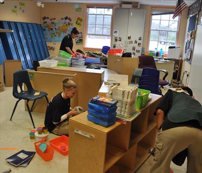 three workers cleaning inside a classroom